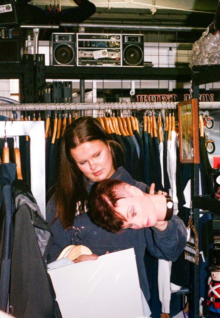 Two shoppers posing among vintage clothing racks, mannequin heads and retro decor at My Dead Grandpa Adelaide