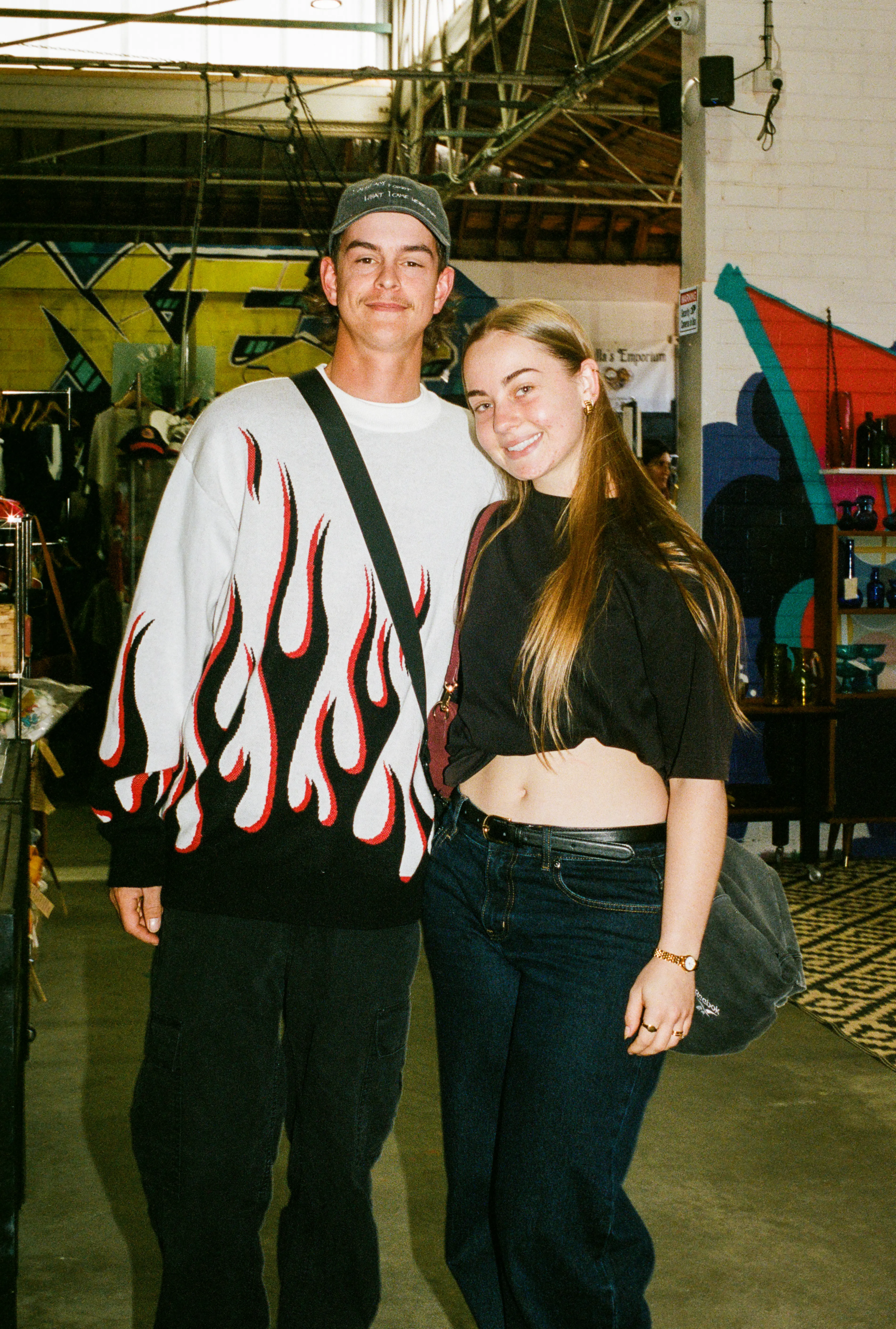 Two shoppers wearing a flame jumper and black crop top inside an Adelaide vintage store.