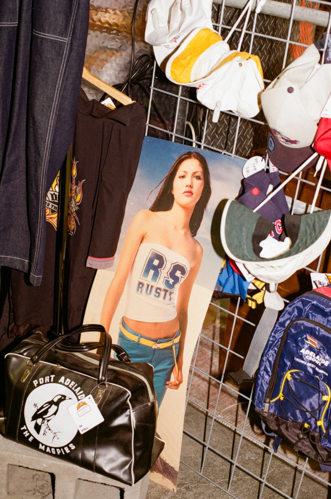 Vintage Adelaide Crows sports bag, caps, backpack and early 2000s fashion poster on display.