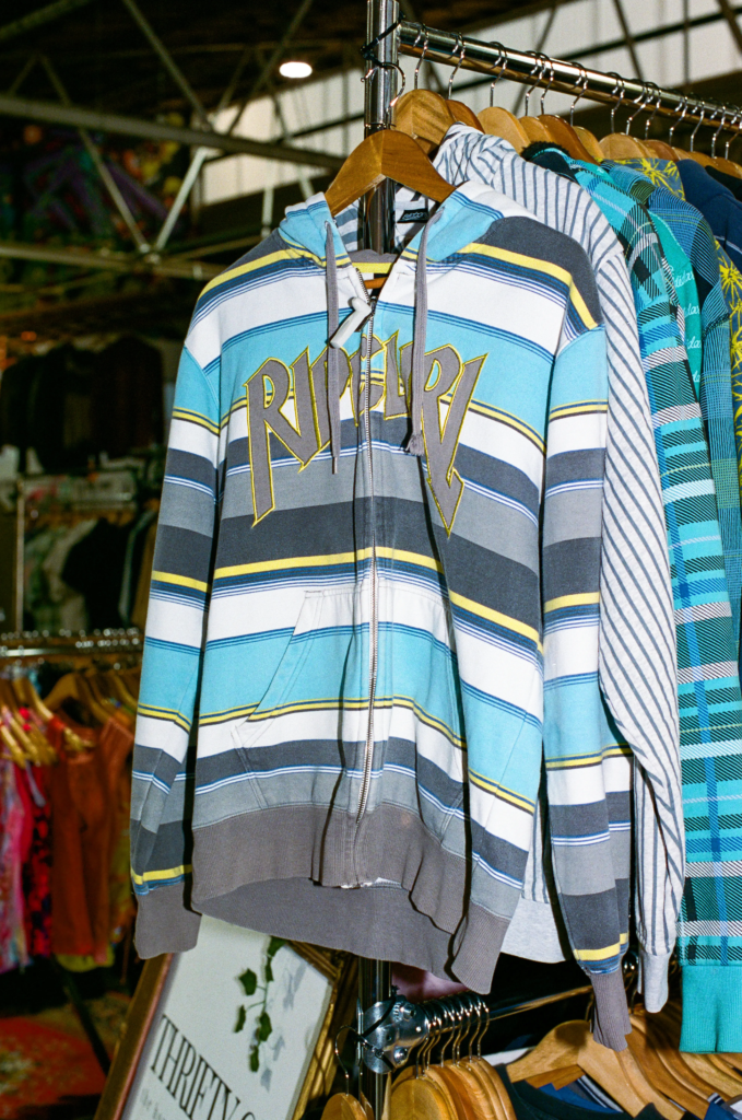 Blue and grey striped vintage Rip Curl zip-up hoodie hanging on an Urban Relics clothing rack.