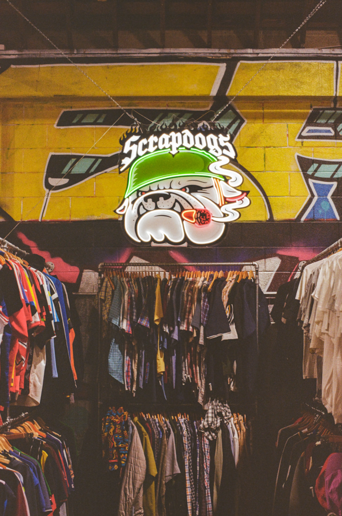 Scrapdogs vintage clothing stall with graffiti wall, illuminated logo and racks of retro streetwear in Adelaide