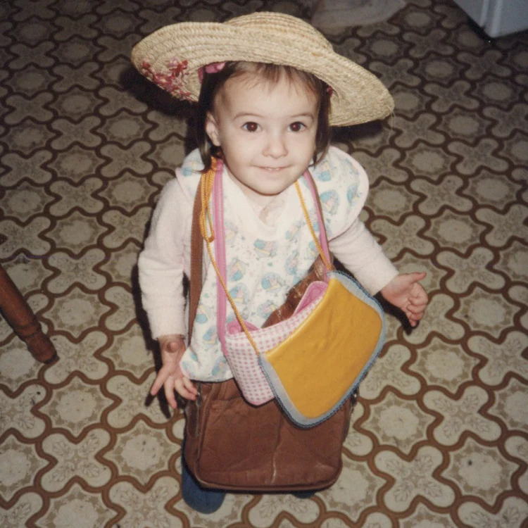 Childhood photo of Liv the Thrifty Gal owner wearing a straw hat and carrying a bag.