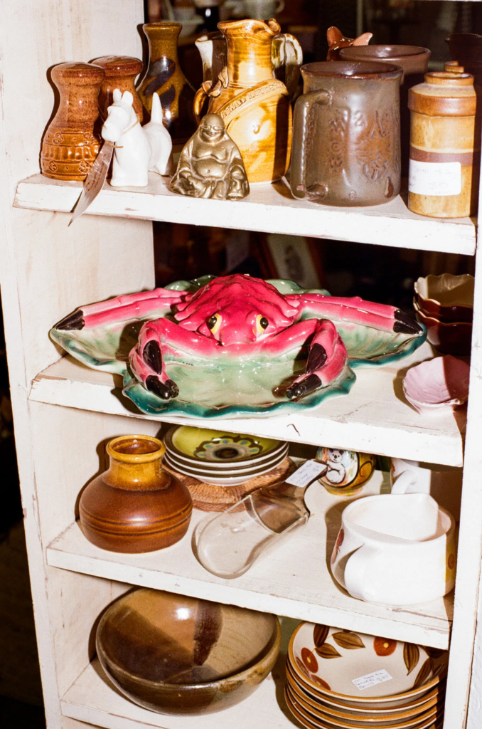 Shelf of vintage ceramics, pottery and a pink crab dish at Collectable Clutter Adelaide.