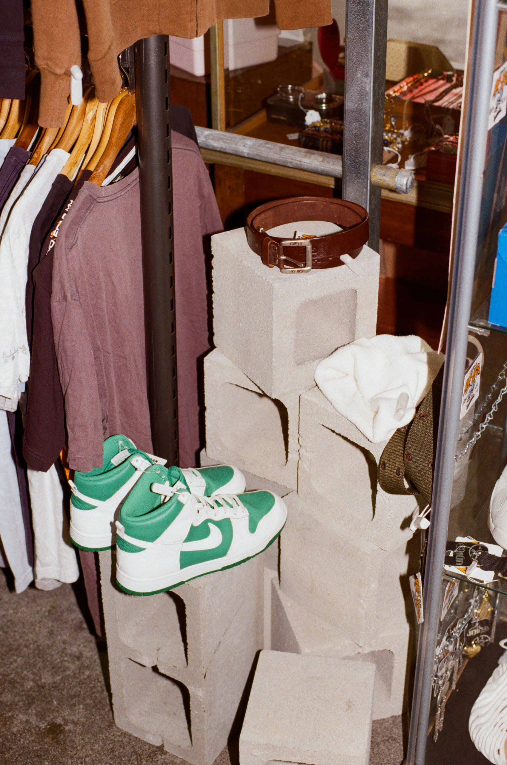 Green and white high-top sneakers, a brown leather belt and vintage clothing displayed on concrete blocks.